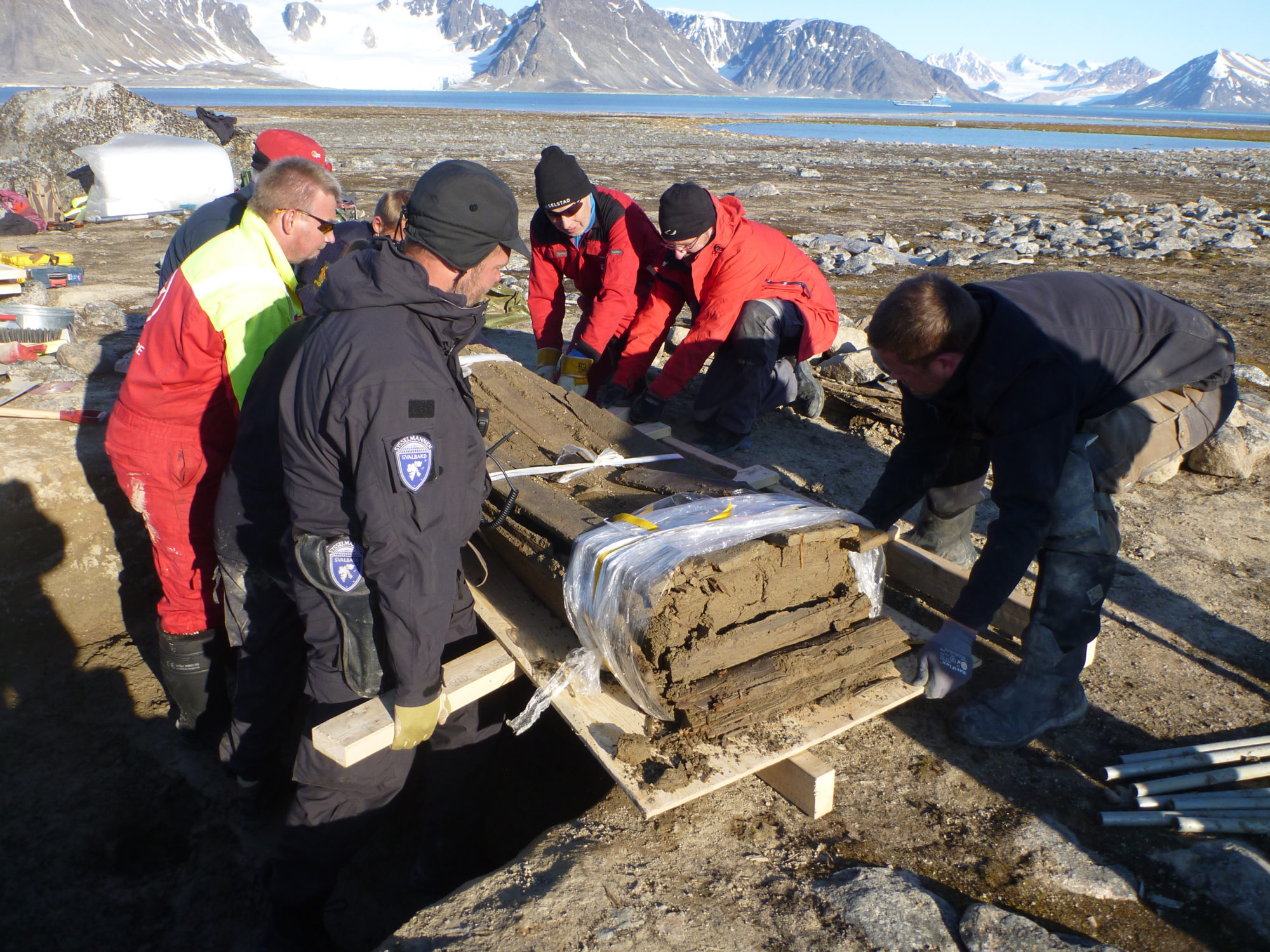 Arkeologene er bekymret for at permafrostens konserverende virkning på kulturminnene er i ferd med å bli borte. I 2017 ble det utgravd en grav midt på Smeerenburgsletta, for å undersøke graden av nedbrytning i et område som ikke er erosjonsutsatt. Kisten ble gravd frem, og fraktet inn som et helt preparat til Svalbard museum, lagt i fryseren, og utgravd i sin helhet innendørs to måneder senere.» Foto Ingrid Sommerseth/Terje Carlsen, Sysselmannen på Svalbard