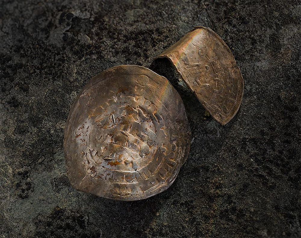 Sølvmyntene, to dirhemer, som trolig er preget i Usbekistan rundt år 930, er kanskje det mest spennende innslaget i gravfunnet. De forteller om en person som kanskje også hadde forstand på handel, i tillegg til å kunne bruke sverd. Foto: Åge Hojem, NTNU Vitenskapsmuseet  