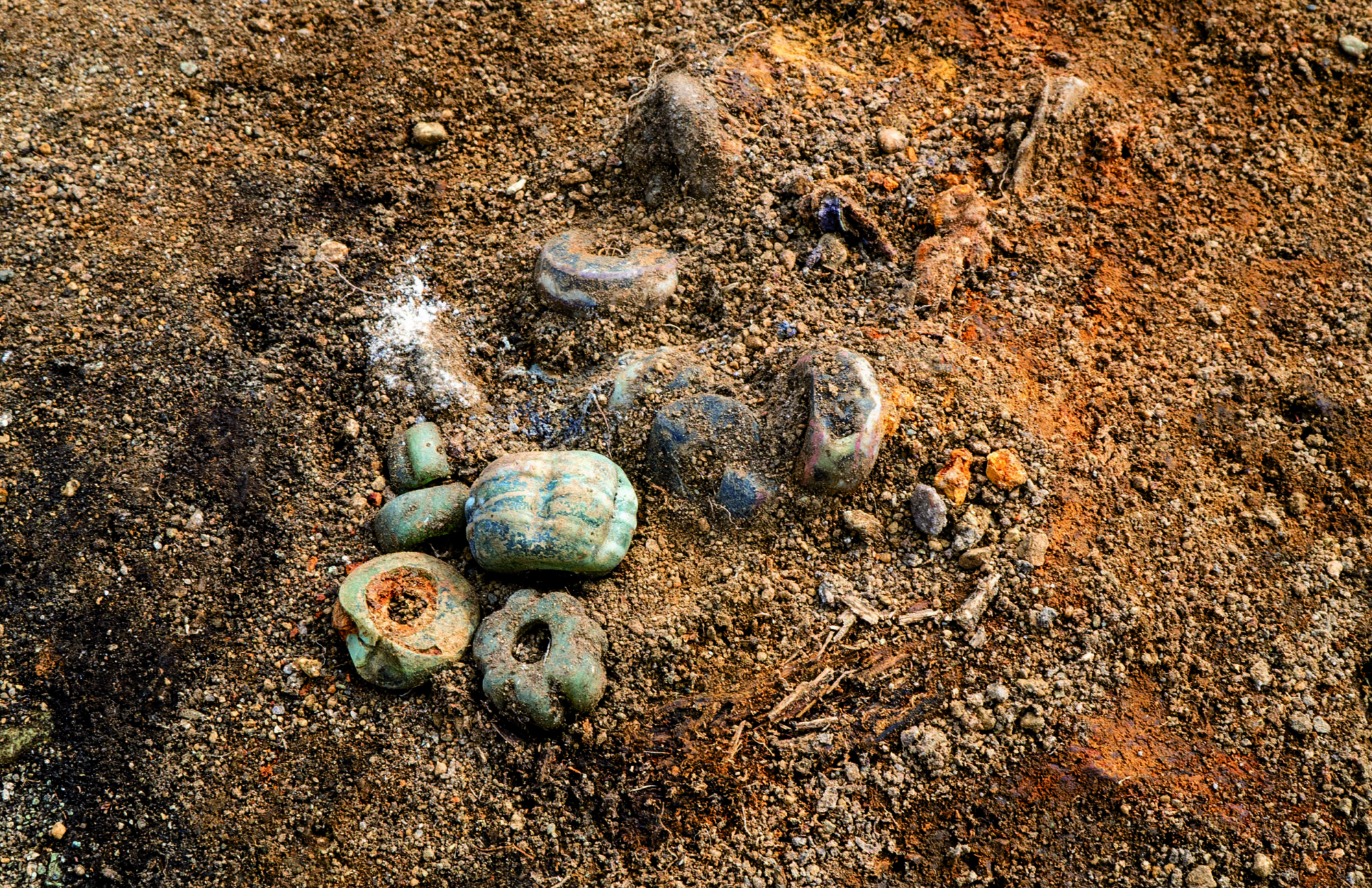 Slik lå glassperlene i kvinnegraven inntil dødehuset. Trerester rundt perlene viser at de har ligget i en liten trebolle eller lignende. Foto Raymond Sauvage, NTNU Vitenskapsmuseet