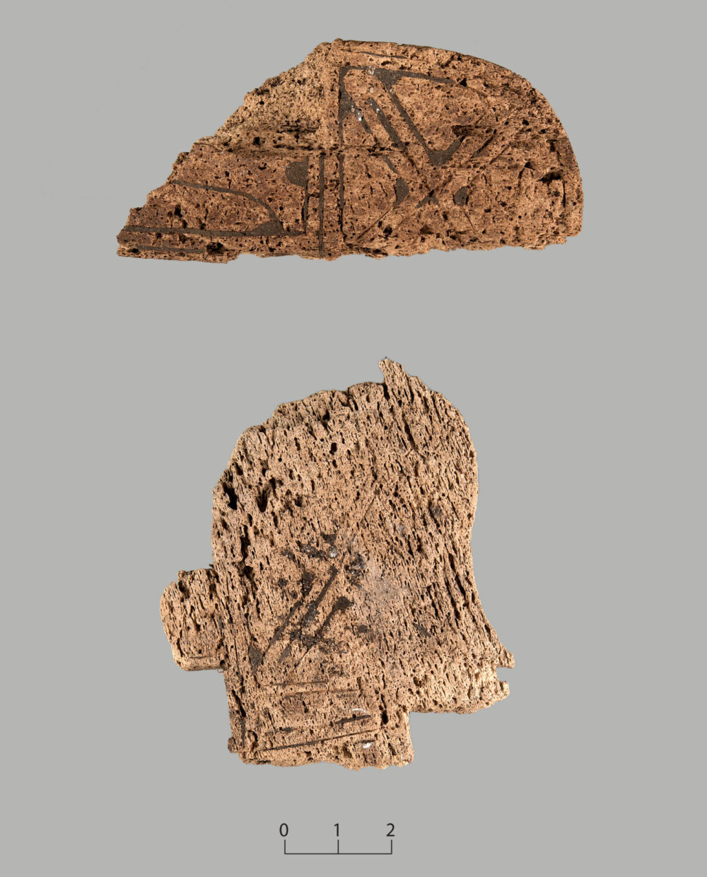 fig8b Løsrevne fragmenter fra hvalbeinsplata. Det nederste fragmentet er et stilisert hode i profil, som trolig forestiller et menneske. Foto: M. Hovind, UM